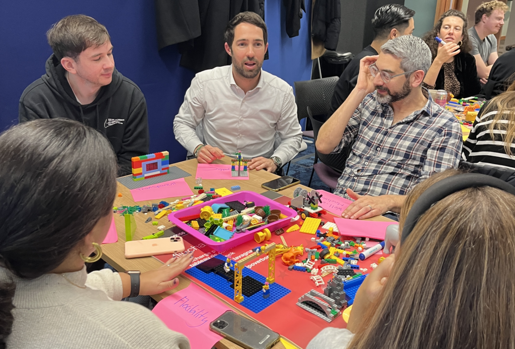 A team in deep discussion at a table full of lego